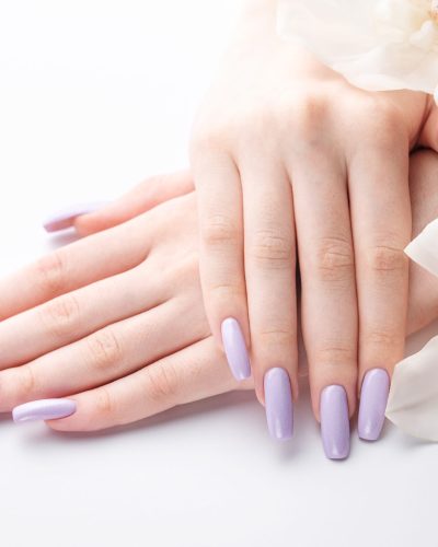 Girl's hands with delicate purple manicure and orchid flowers. The concept of beauty and body care.