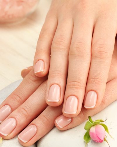 Spa concept. Woman hands with beautiful rose petals on wooden background, close up